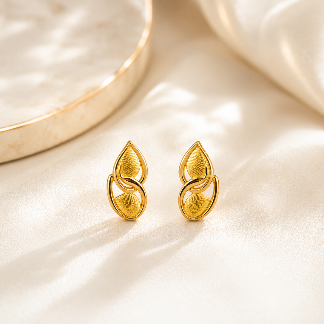 Gold earrings on a beige fabric background