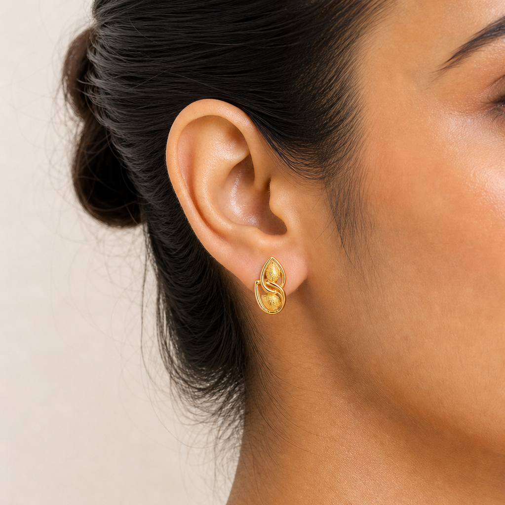 Close-up of a person wearing gold earrings with a neutral background