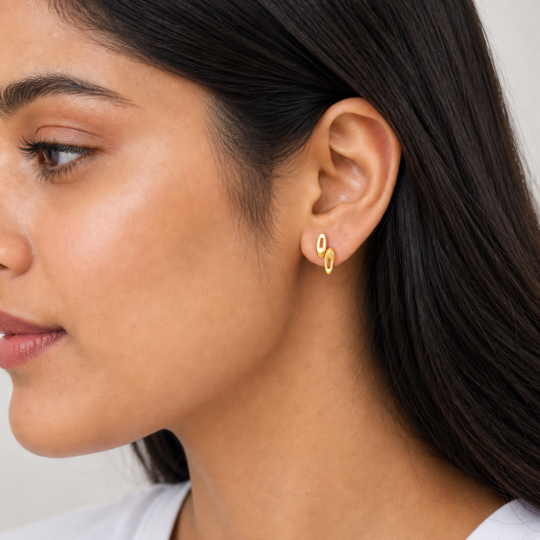 Close-up of a woman wearing gold earrings with a neutral background