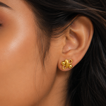 Close-up of a woman's ear wearing a gold earring with a blurred background